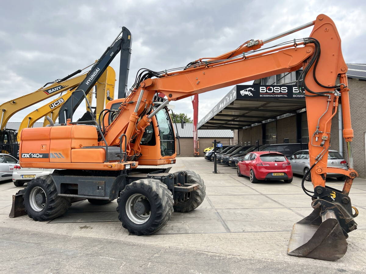 Pelle-Doosan-DX140W-02 Pelle sur pneus Doosan DX140W 2010 – 14,8T – 7857h – Occasion – Image 1
